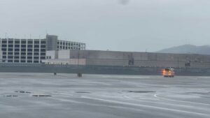 An emergency vehicle with its sirens on drives on an airport runway on a rainy day,