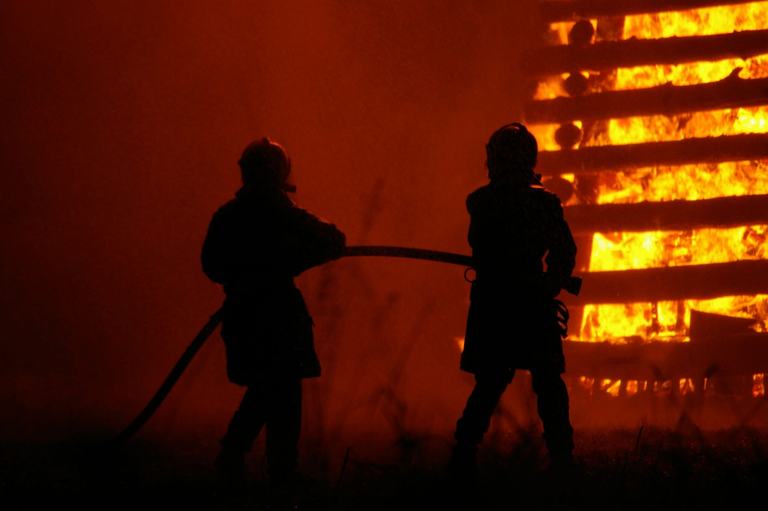 Two firefighters fight a house fire.