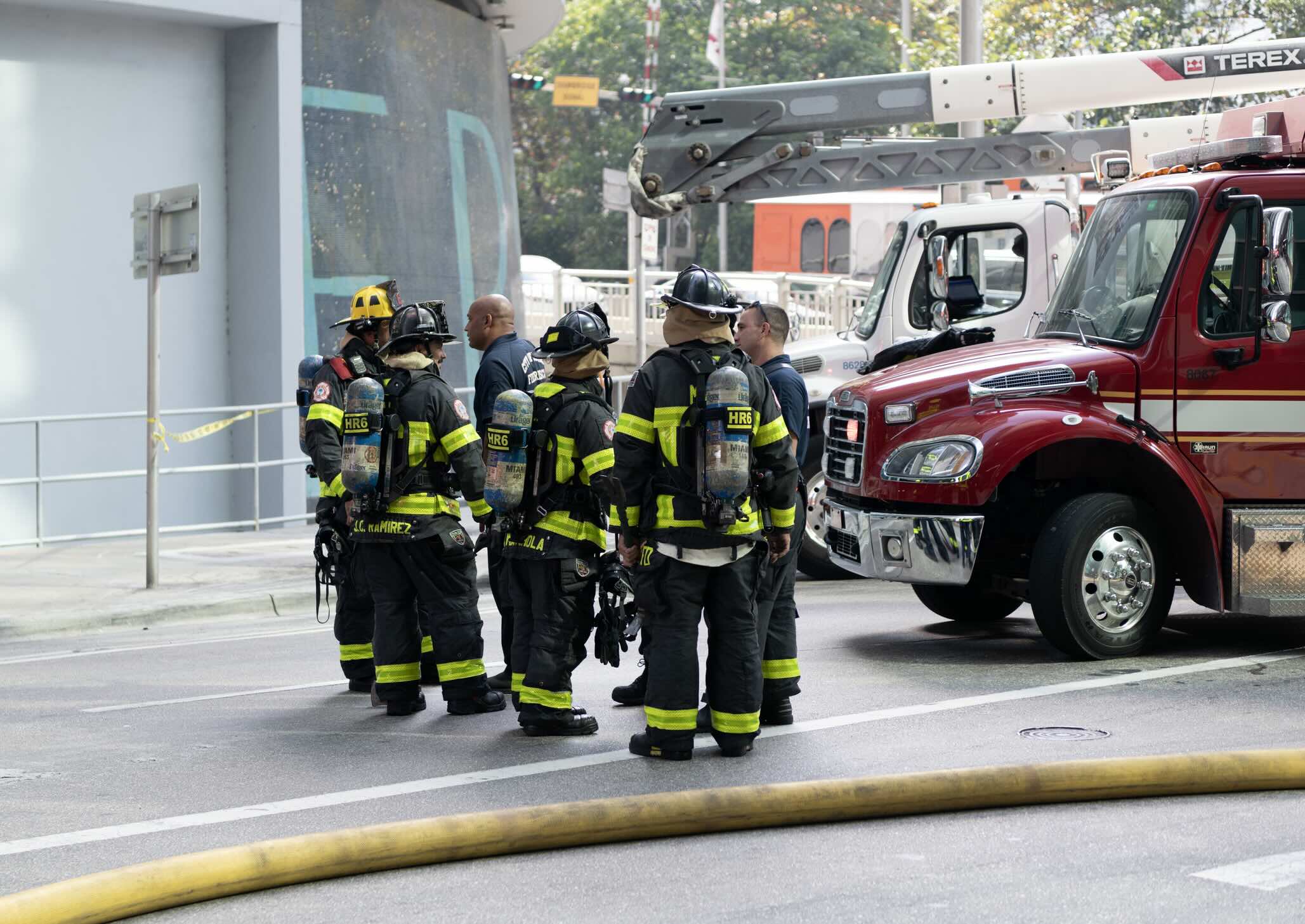 Firefighter teamwork in fire suit on rescue duty using water from hose. Fireman of Miami. 911 emergency. Firefighter in uniform. Team of fireman.