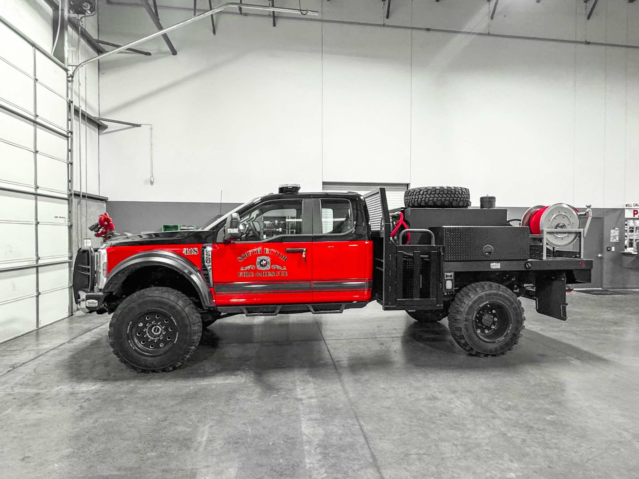 Side view of a Fouts Fire apparatus personalized for South Ector Fire & Rescue parked in a garage.